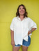 Woman wearing a white shirt and denim shorts against a yellow wall