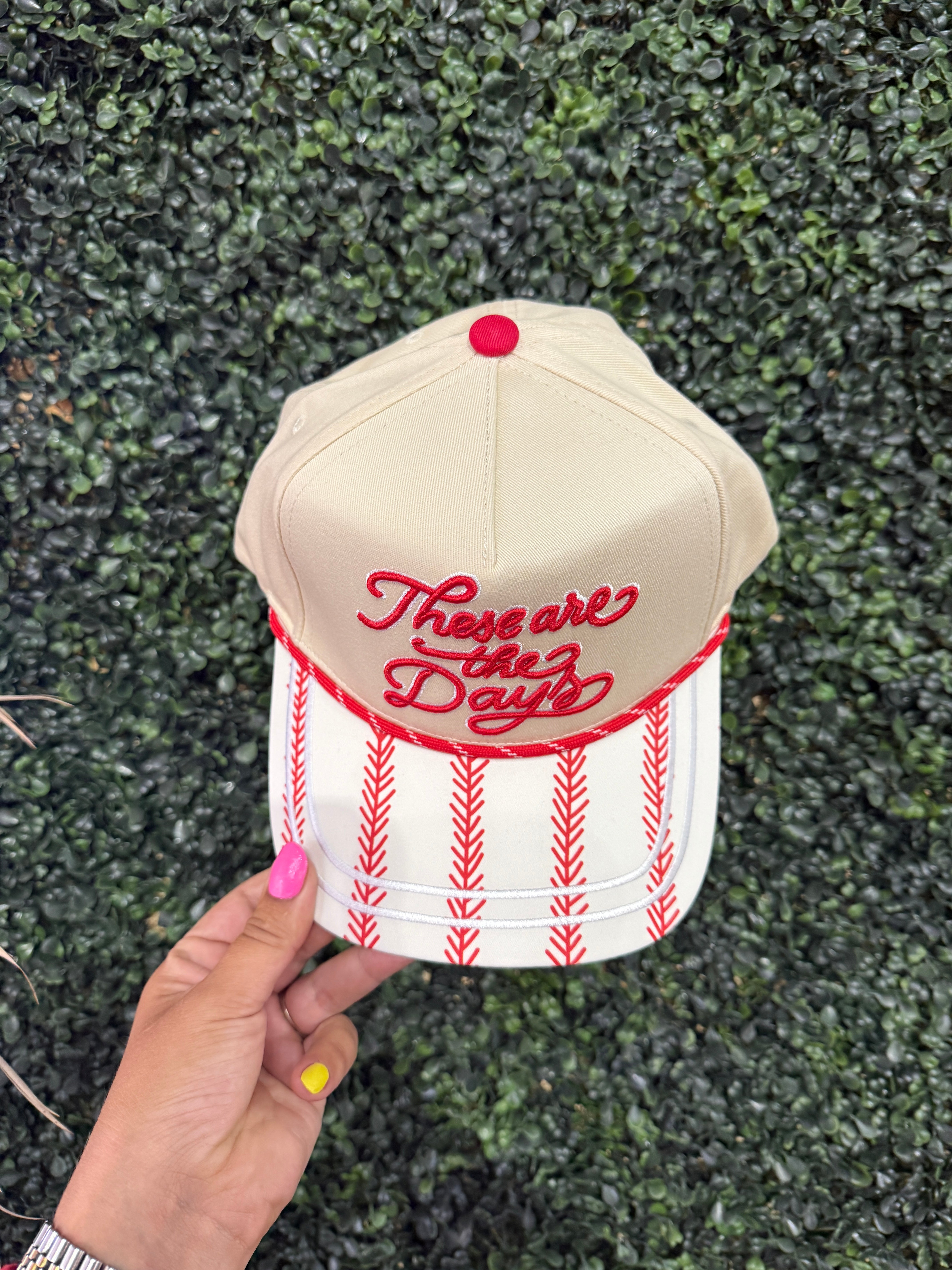 Beige cap with red text and white pattern held against a green textured background