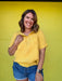 Woman wearing a yellow shirt and blue shorts against a yellow background